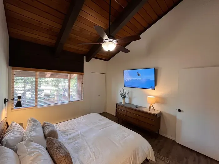 Bedroom with a king bed, cealing fan, 65" smart TV and a beautiful view of the Sherwins.