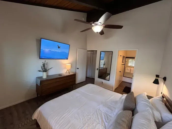 Bedroom with a king bed, cealing fan, 65" smart TV and attacherd bathroom.  Bathroom can be accessed from either the hallway or bedroom with privacy doors securing both entrances.
