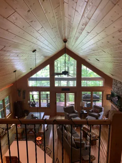 View overlooking great room out to covered deck & lake from top of stairs / upper level closed sleeping loft entry.  (Accurate Illustration, AI Enhanced Decor Due to Build In Progress)