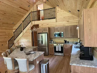 View from main level dining area looking across open floor plan kitchen, with the stairway leading up to the 2nd floor closed sleeping loft with 4-built in twin beds.