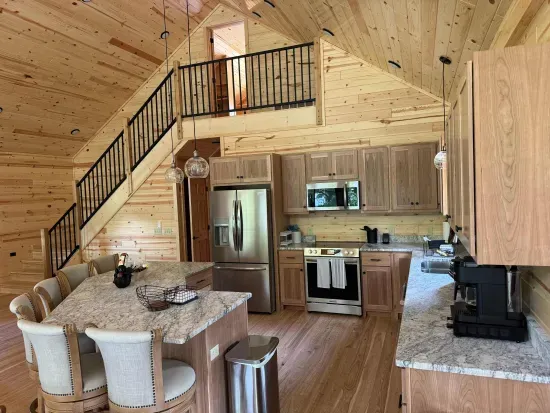 View from main level dining area looking across open floor plan kitchen, with the stairway leading up to the 2nd floor closed sleeping loft with 4-built in twin beds.