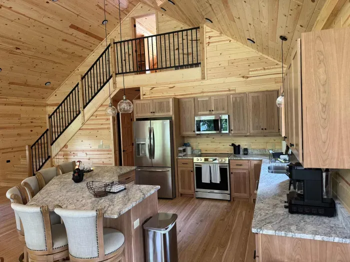 View from main level dining area looking across open floor plan kitchen, with the stairway leading up to the 2nd floor closed sleeping loft with 4-built in twin beds.