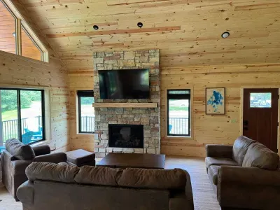Main level entry view across Lakeside #1 great room, 6-person dining kitchen island, 6-person dining table, family room around gas fireplace, 65" smart TV, access to lake side wrap around deck with BBQ