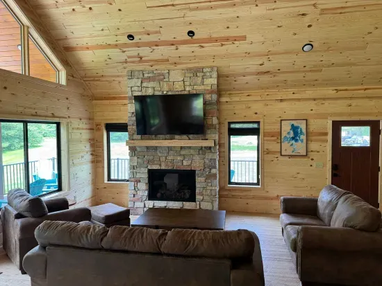 Main level entry view across Lakeside #1 great room, 6-person dining kitchen island, 6-person dining table, family room around gas fireplace, 65" smart TV, access to lake side wrap around deck with BBQ