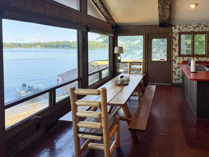 View across the dining table and kitchen area with direct access to the deck overlooking the lake, providing stair access to the lake / boat dock / swimming area below as well as stair access to the expansive BBQ and fire pit area.