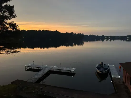 End of sunset view from 5RK Lodge deck off kitchen dining area, looking north across Little Round Lake to HWY B bridge over entrance to Big Round Lake - you can see The Dock restaurant and Round Lake Marina. There is room for guests to dock 3-4 boats