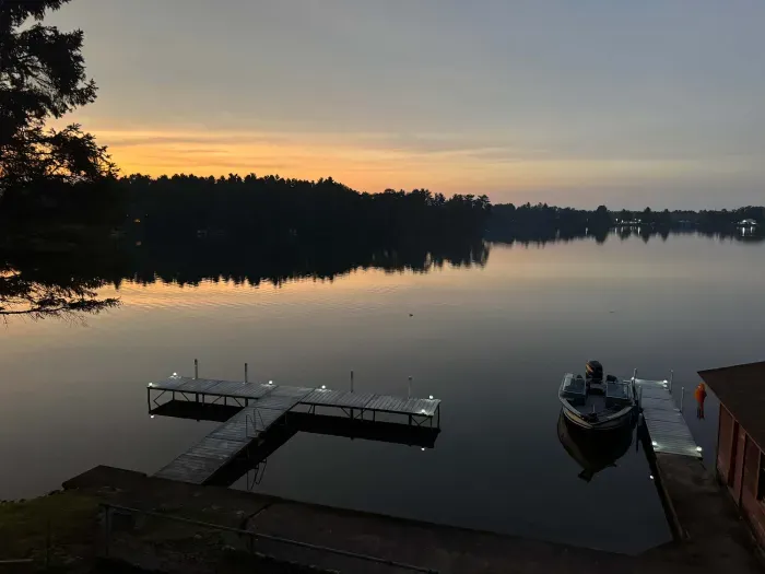 End of sunset view from 5RK Lodge deck off kitchen dining area, looking north across Little Round Lake to HWY B bridge over entrance to Big Round Lake - you can see The Dock restaurant and Round Lake Marina. There is room for guests to dock 3-4 boats