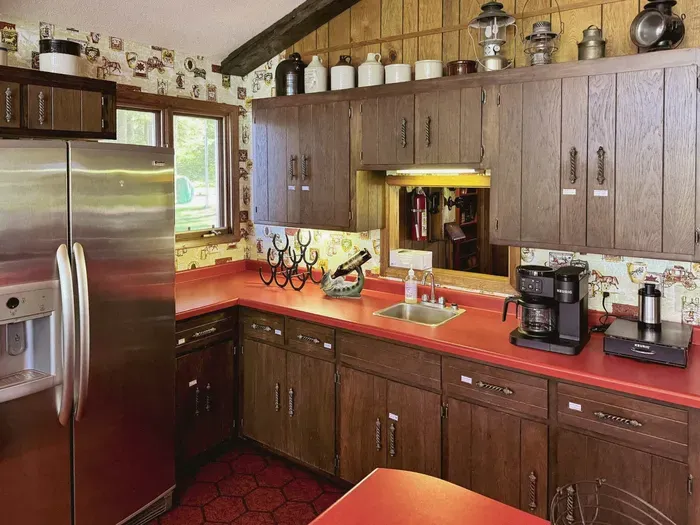 View of the wet bar within the full kitchen space with a serving window to the main entrance hallway & additional wine & beverage refrigerator 