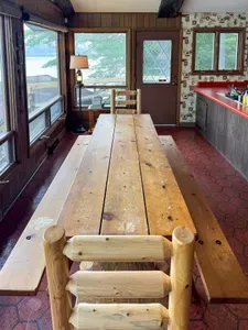Close up view of the rustic dining table with exit / direct access to the deck overlooking the lake, providing stair access to the lake / boat dock / swimming area below as well as stair access to the expansive BBQ and fire pit area.
