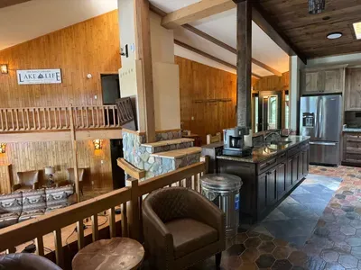 View from sitting area looking across the bi-level open floor plan with continuous views of the lake and floor plan that follows the contour of the lots' peninsula shoreline.  Gourmet eat-in kitchen, large great room, dining area, 65" smart TV, +more