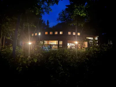 Nighttime lakeside view of the Peninsula Lakehouse and the expansive wrap around deck and path leading to private lakes access, boat dock, swimming area, and lake side fire pit.