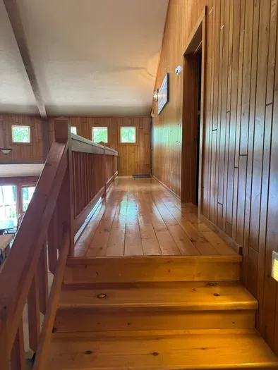 View from front entry foyer of stairs up to master bedroom suite and private lake view balcony.  Master bedroom suite is setup with King Bed and connected to dual vanity master bathroom with sky-lights, cedar closet, and walk in tile rain shower.