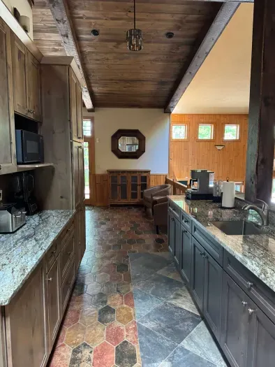 View from gourmet eat-in kitchen of coffee bar, 2nd farm sink, and lots of counter space looking forward towards the sitting room connecting to the screened in porch and wrap around deck & BBQ area for the Peninsula Lakehouse.