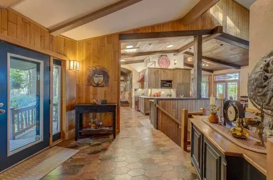View from the main entry foyer facing the modern, updated open kitchen and stairs leading down to main level great room and hearth seating area.