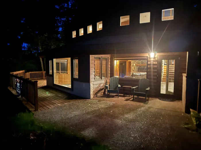 Nighttime lakeside view of the Peninsula Lakehouse and the expansive wrap around deck and path leading to private lakes access, boat dock, swimming area, and lake side fire pit.