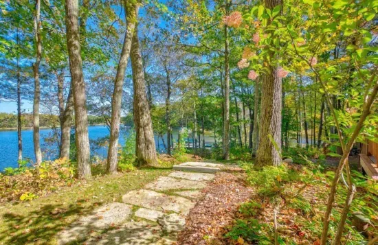 Well manicured lakeside pathway from the Peninsula Lakehouse down to the private boat, fire pit, and swimming dock along shallow sandy beach on crystal clear Little Round Lake with easy boat access to the entirety of Round Lake.