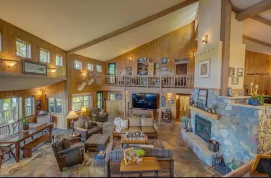 Second tier view from the kitchen side of the house, looking down to the main level great room / hearth room living area within the Peninsula Lakehouse, with lake views from every place in the room!