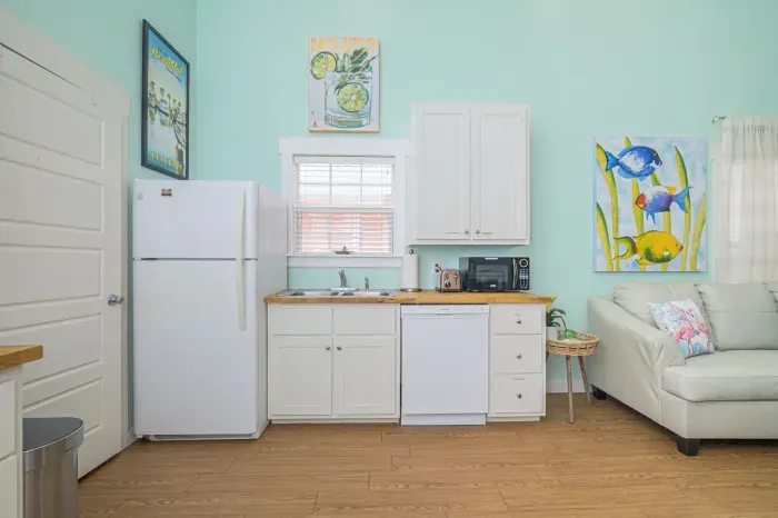 Full-size fridge and cupboard full of dishes