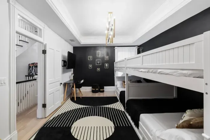 Featuring four full-size adult bunk beds and two twin-size trundle beds with integrated stairs, animal heads wall decors, black-and-gold chandelier, working desk, 55'' Roku Smart TV and accent chair.