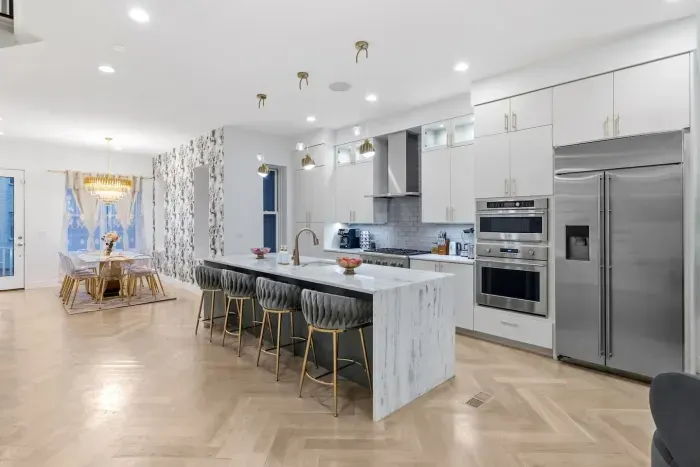 Marble countertops, high-end Monogram appliances, European-style cabinetry, three arched gold pendant lights, premium cookware, bakeware, utensils, and serving essentials, fine dishes and silverware, dual coffee system, cocktail shaker set.
