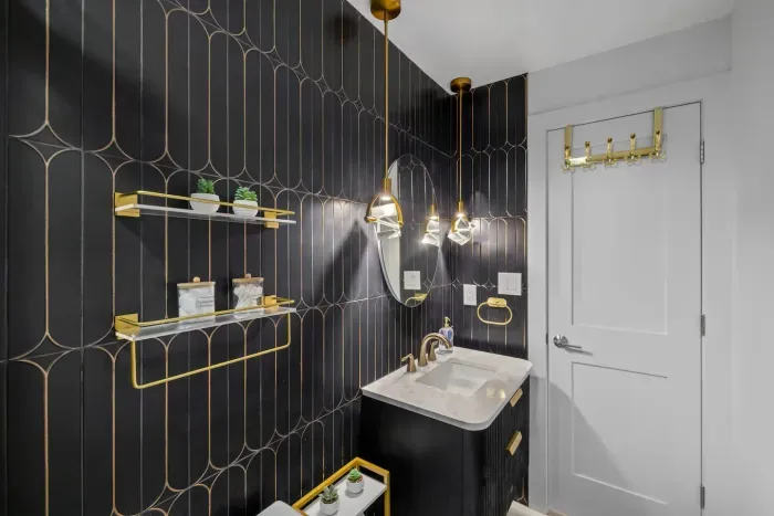 Featuring high-end black-and-gold wall tiles, diamond-cut glass pendant lights, delta shower system, and all-gold fixtures throughout.
