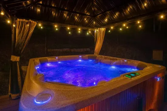 Luxury Hot Tub with Pergola providing shading, curtains, mosquito net and lighting.  Outdoor sitting bench on the side deck.  Enjoy the Hot Tub even in the rain and snow!