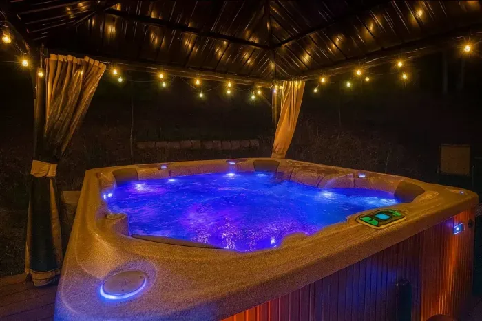 Luxury Hot Tub with Pergola providing shading, curtains, mosquito net and lighting.  Outdoor sitting bench on the side deck.  Enjoy the Hot Tub even in the rain and snow!