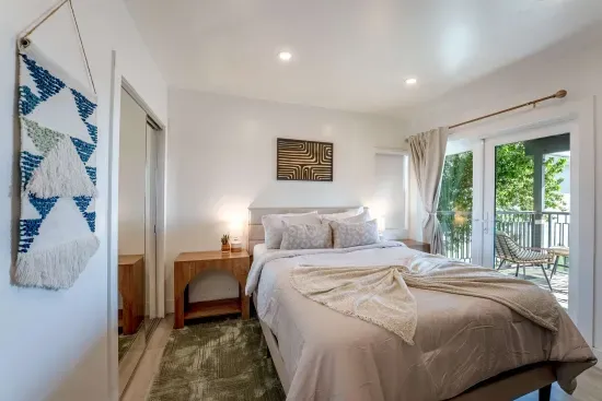 Downstairs bedroom with TV and private balcony with city views