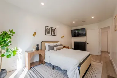 downstairs bedroom with full bed, TV, and access to the driveway that leads to the backyard.
