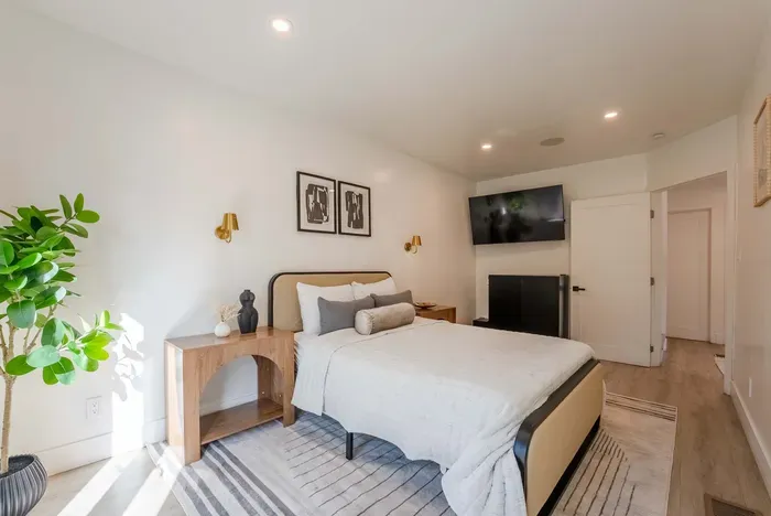 downstairs bedroom with full bed, TV, and access to the driveway that leads to the backyard.