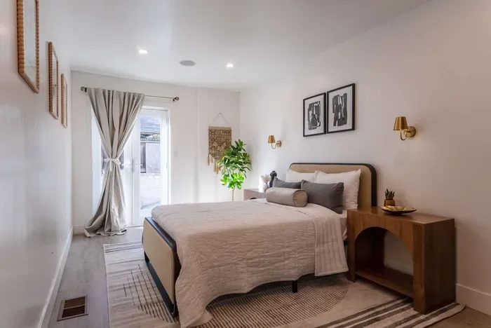 downstairs bedroom with full bed, TV, and access to the driveway that leads to the backyard.