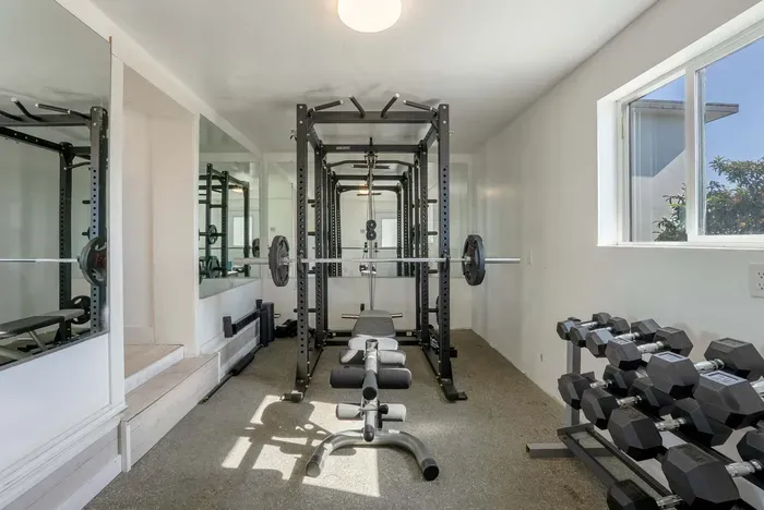 Gym with bench press, dumbbells.