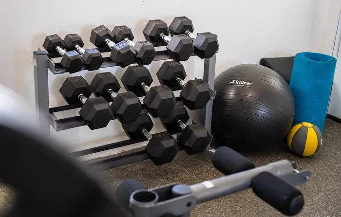 Gym with bench press, dumbbells.