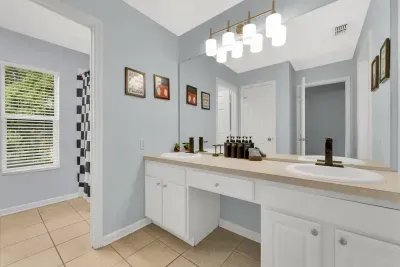 Full Bathroom 3: Soft blue walls, a long vanity with modern lighting, framed art, and shampoo, conditioner, and body wash provided!