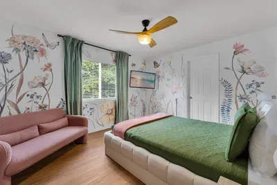 Bedroom 3: Whimsical floral and butterfly mural wallpaper wraps this garden-inspired retreat with a plush blush loveseat!