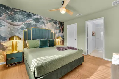 Bedroom 2: Emerald walls, a woodland mural, and a gold-trimmed upholstered bed for a chic retreat!