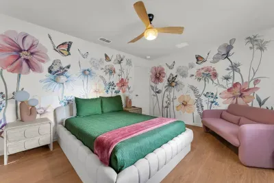 Bedroom 3: A blooming floral and butterfly mural surrounds a cozy queen bed and blush loveseat for a dreamy garden escape!