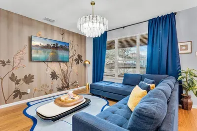 Third Living Area: Blue tufted sectional under a crystal chandelier, with a wall-mounted smart TV!