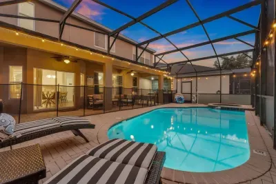 Screened Pool: The pool is framed by the covered patio and dining area, all lit up as the sun sets!