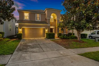 Elegant two-story home with warm lighting, arched entry, and great curb appeal