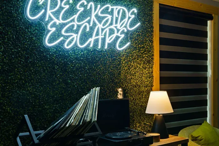Cozy lounge corner with neon sign, vinyl setup, and warm ambient lighting