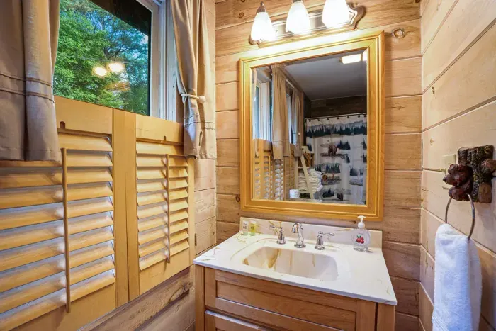 Cozy cabin bathroom with rustic wood finishes and bright vanity lighting