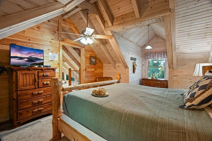 Cozy loft bedroom with rustic wood interiors, TV, and charming cabin style