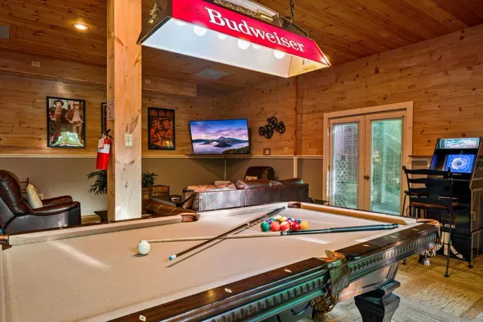Cozy wood-paneled game room with pool table, TV, and arcade fun