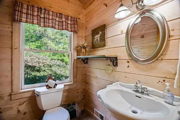 Charming wood-paneled bathroom with bright window and rustic cabin touches