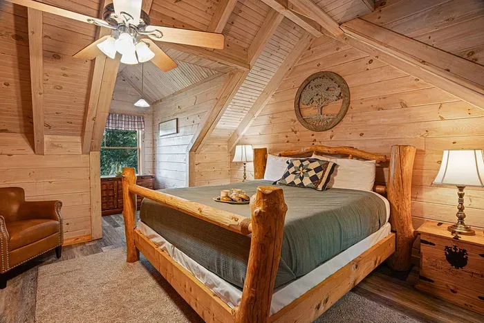 Rustic loft bedroom with log bed, vaulted wood ceilings, and cozy cabin charm