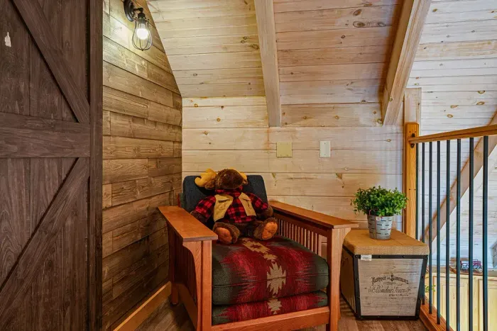 Cozy cabin loft nook with rustic chair, barn door, and warm wood accents