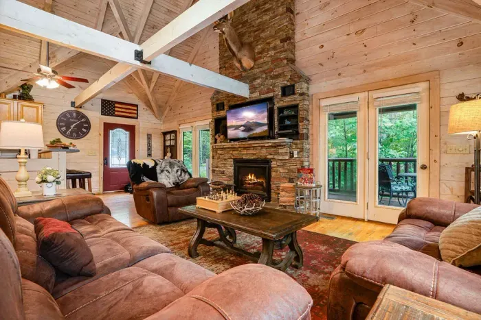 Cozy rustic great room with stone fireplace, leather seating & deck views