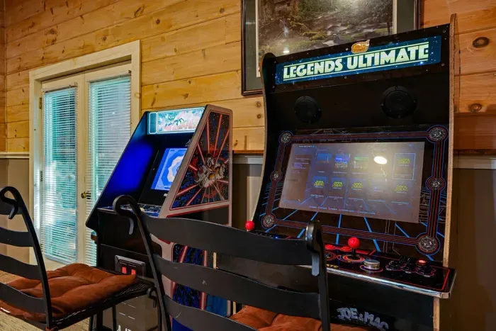 Retro arcade game room with two full-size machines and cozy seating