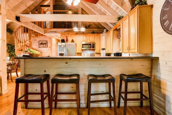 Rustic cabin kitchen with breakfast bar, loft views, and warm wood charm